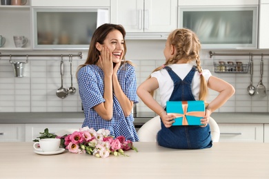 Little daughter congratulating her mom in kitchen. Happy Mother's Day
