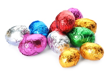 Photo of Many chocolate eggs wrapped in bright foil on white background