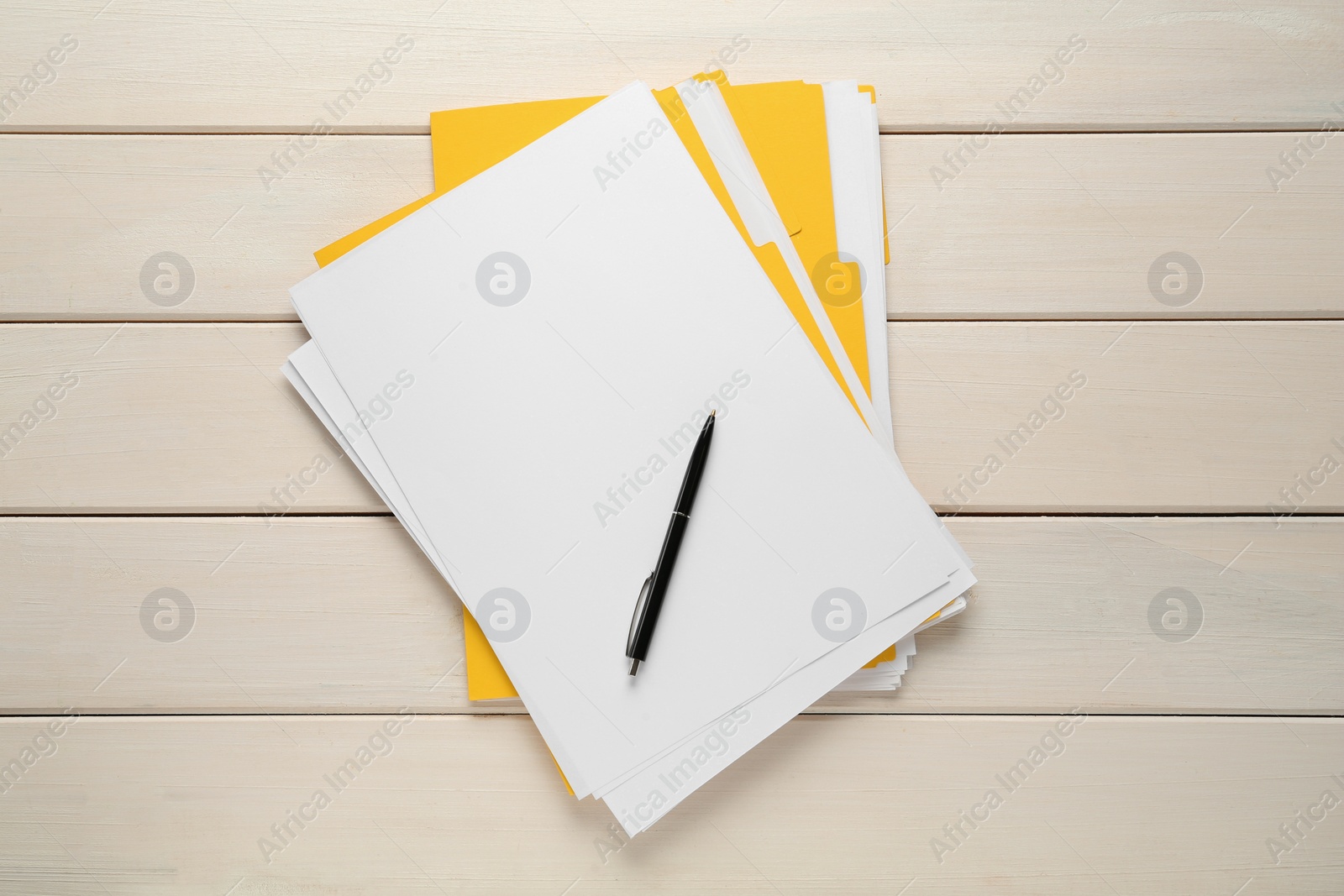 Photo of Yellow files with blank sheets of paper and pen on white wooden table, top view. Space for design