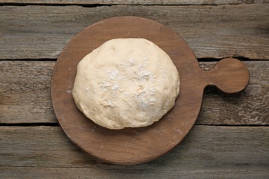 Fresh yeast dough with flour on wooden table, top view