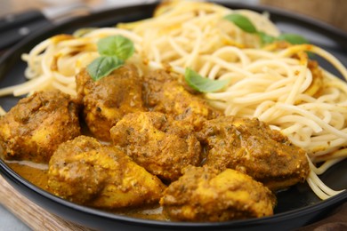 Photo of Delicious pasta and chicken with curry sauce on plate, closeup