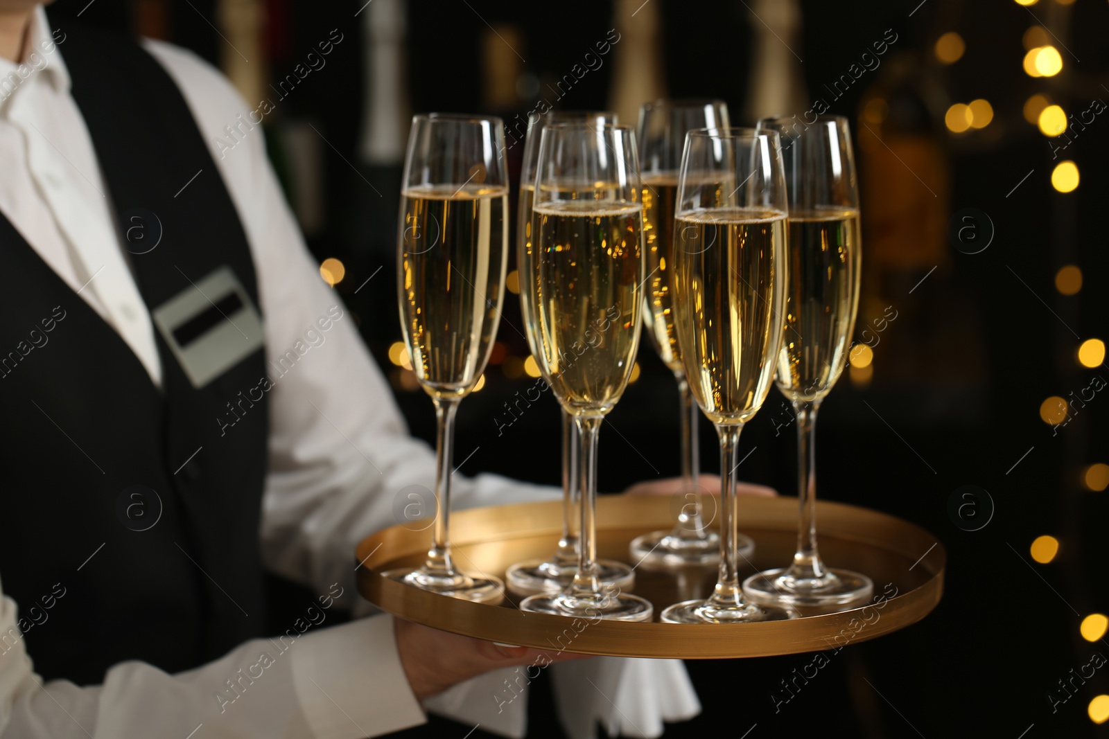 Photo of Waiter holding tray with glasses of champagne on blurred background, closeup