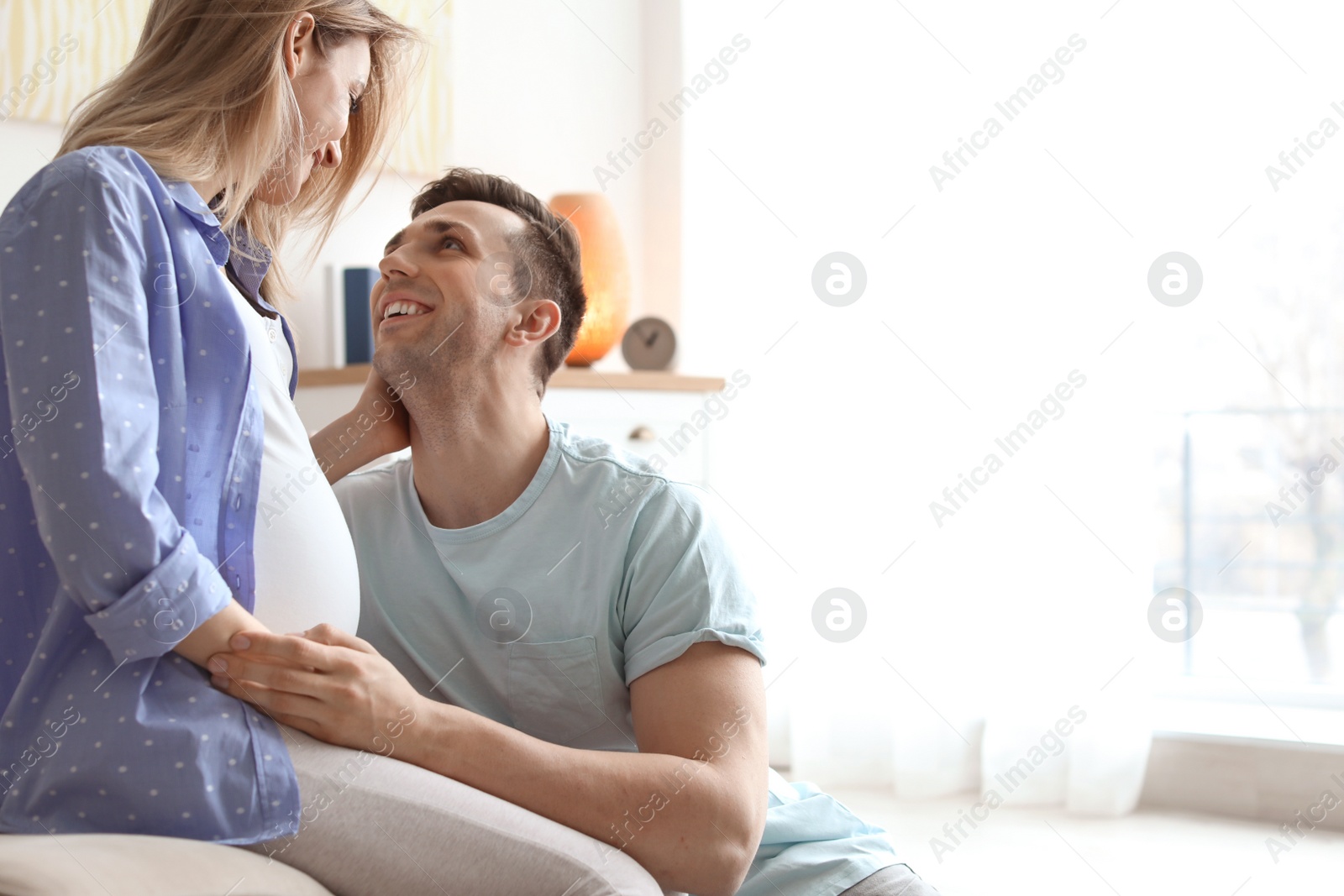 Photo of Young pregnant woman with her husband at home