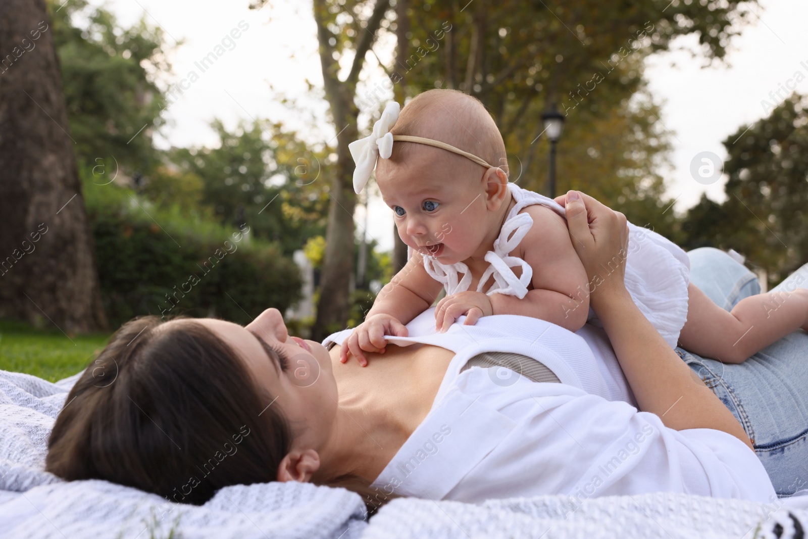 Photo of Happy mother with adorable baby lying in park