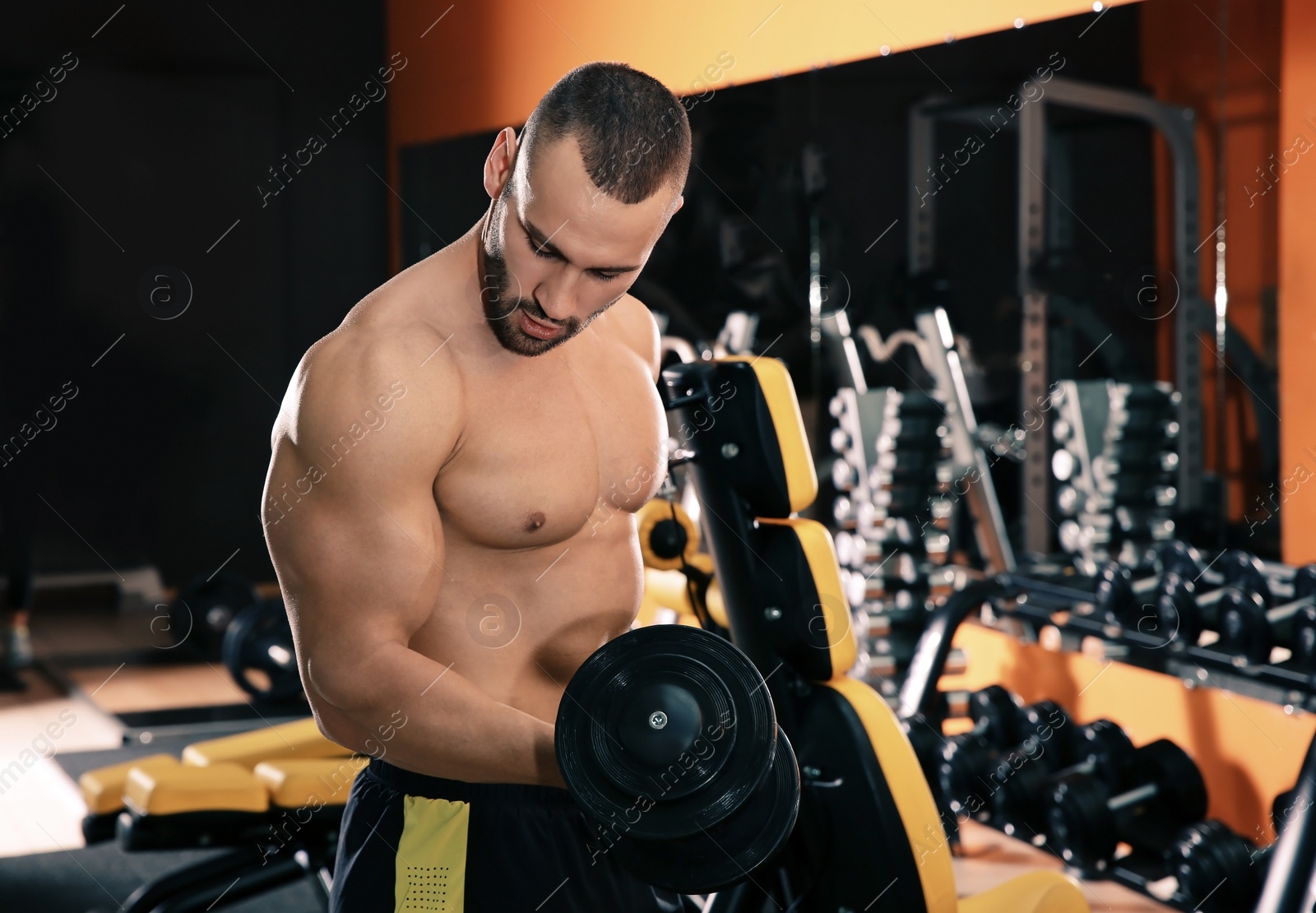 Photo of Strong young man lifting dumbbell in gym