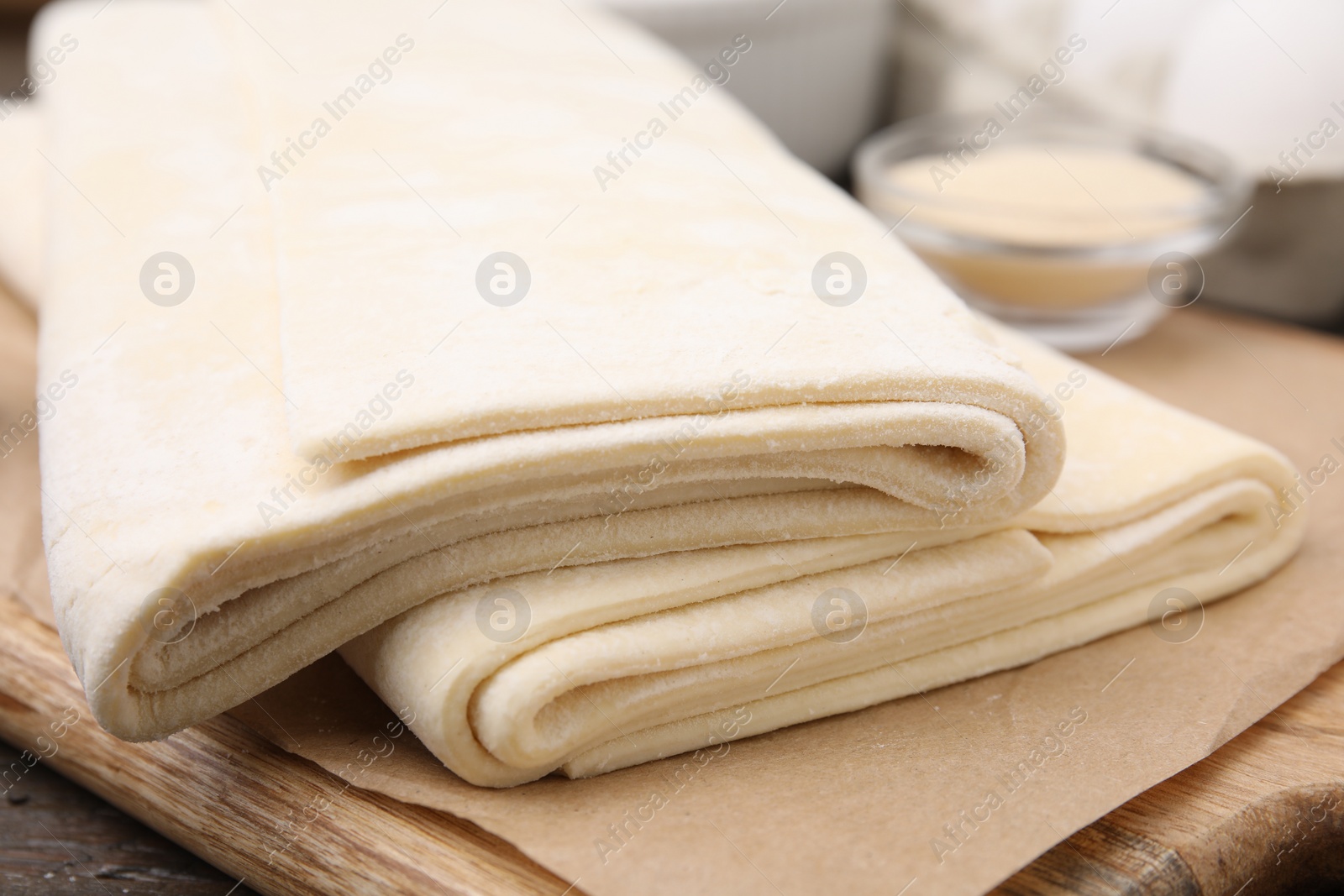 Photo of Raw puff pastry dough on wooden table, closeup