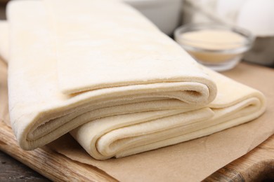 Raw puff pastry dough on wooden table, closeup