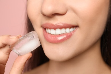 Photo of Young woman with ice cube on color background, closeup. Skin care