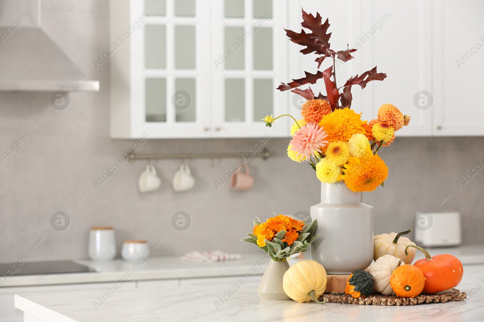 Photo of Beautiful autumn bouquets and pumpkins on marble table in kitchen