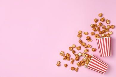 Overturned paper cups with caramel popcorn on color background, top view. Space for text