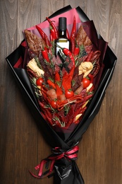 Photo of Beautiful edible bouquet with meat, cheese and vegetables on wooden table, top view