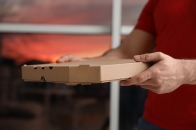 Photo of Courier with pizza box on blurred background, closeup