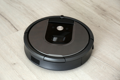 Photo of Modern robotic vacuum cleaner on wooden floor