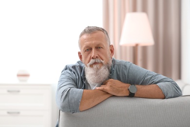 Photo of Portrait of handsome mature man sitting on sofa in room
