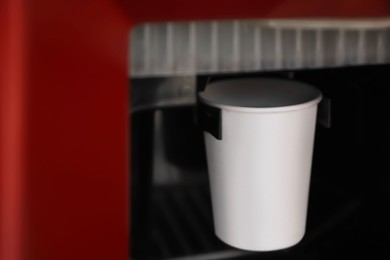 Paper cup with coffee in vending machine, closeup