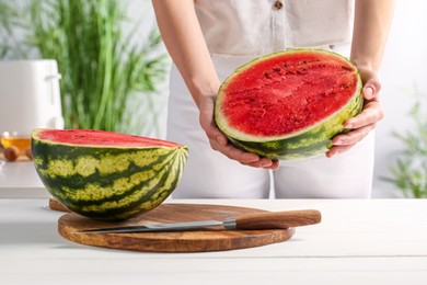 Photo of Woman with delicious cut watermelon at white wooden table in kitchen, closeup