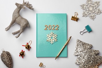 Photo of Turquoise planner and Christmas decor on white background, flat lay. 2022 New Year aims