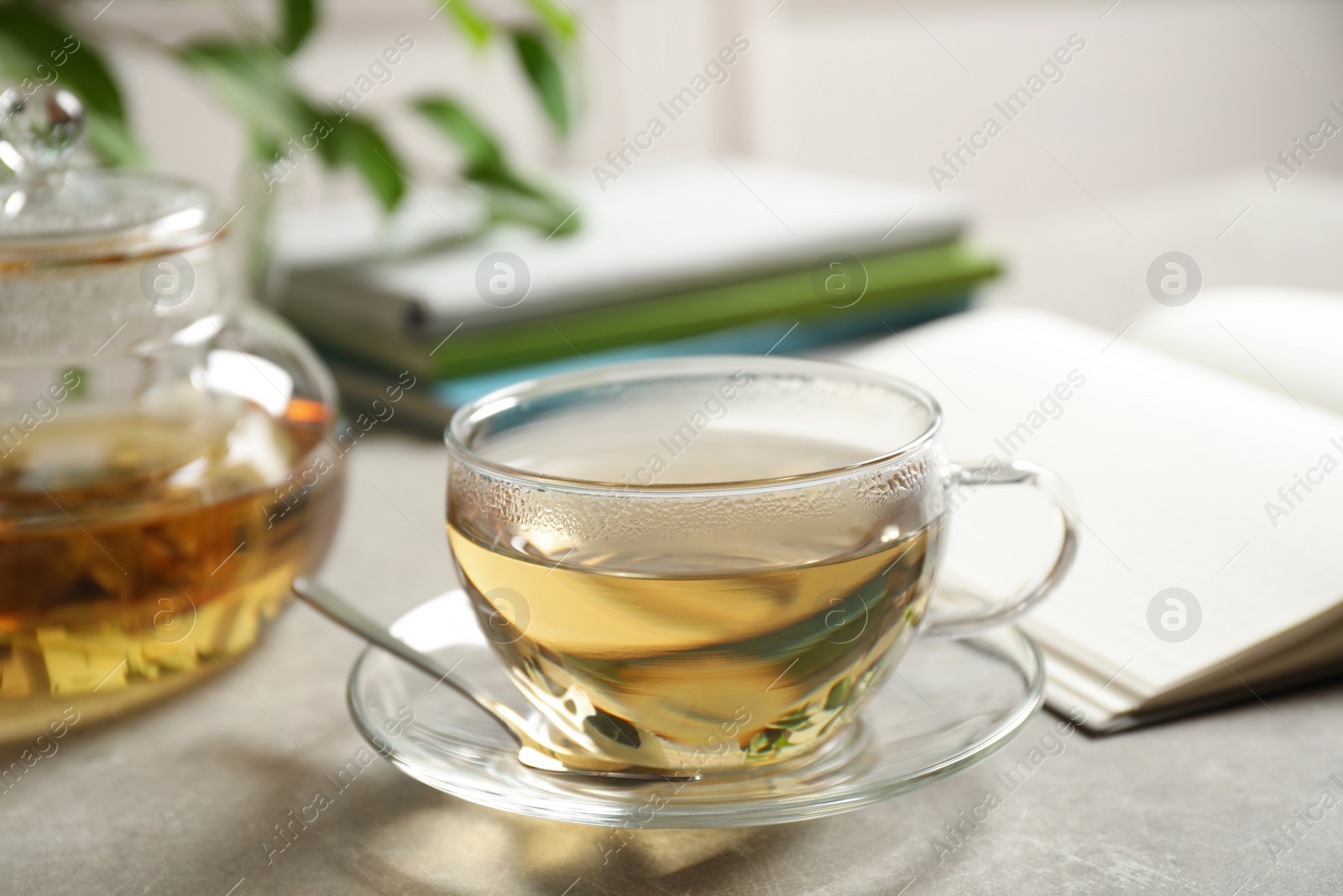 Photo of Tasty hot green tea in cup on grey table