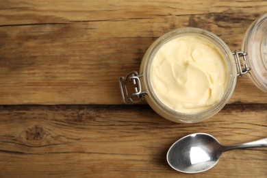 Jar of delicious mayonnaise and spoon on wooden table, flat lay. Space for text