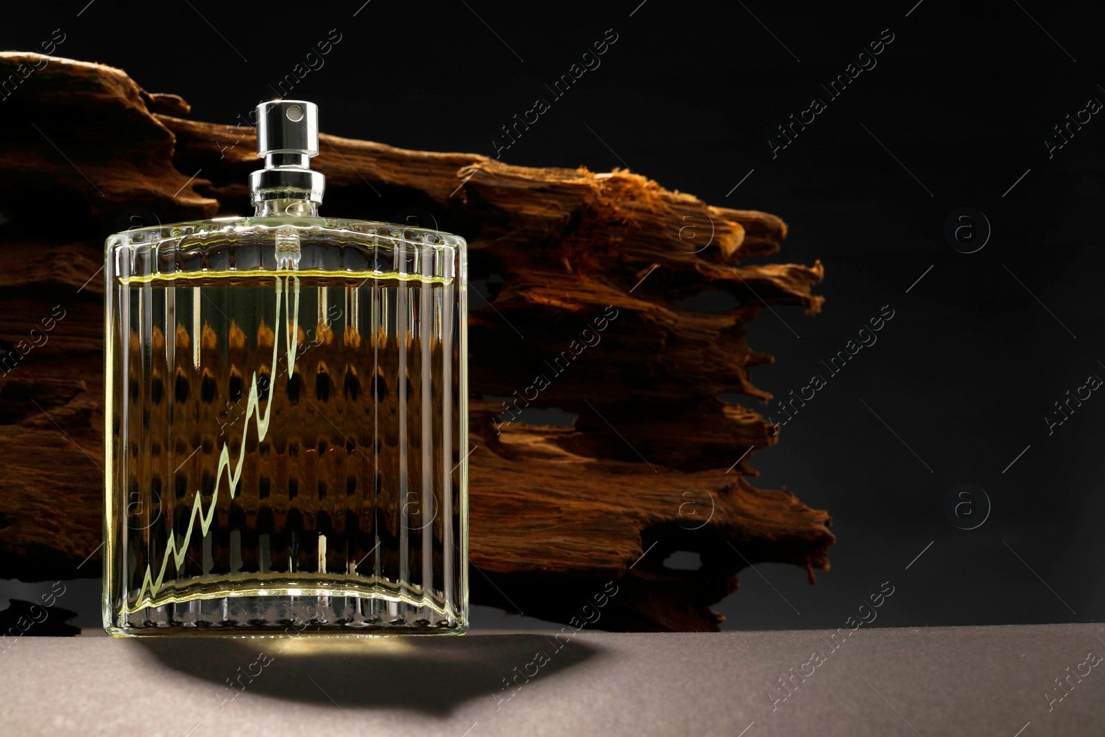 Photo of Luxury men`s perfume in bottle on grey table against dark background, space for text