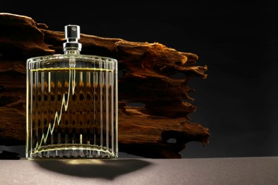 Luxury men`s perfume in bottle on grey table against dark background, space for text