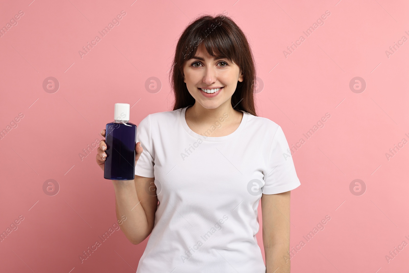 Photo of Young woman with mouthwash on pink background