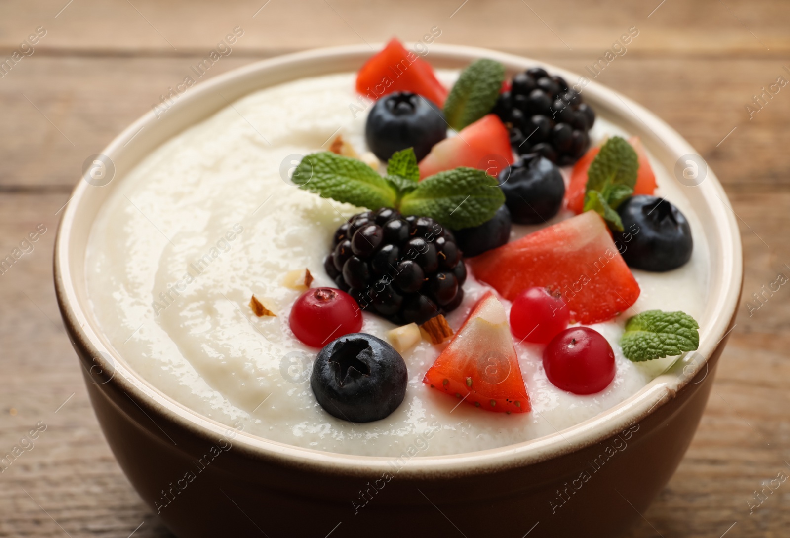 Photo of Delicious semolina pudding with berries on wooden table, closeup