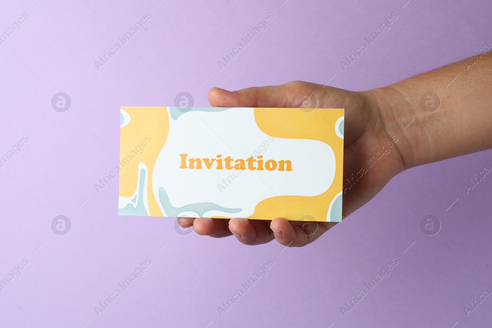 Photo of Woman holding beautiful card with word Invitation on lilac background, closeup