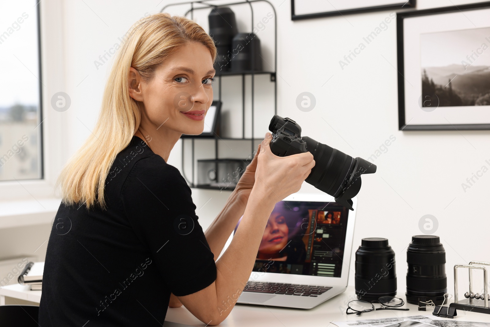 Photo of Professional photographer with digital camera at table in office