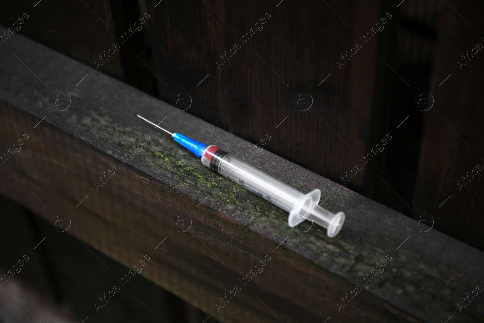 Photo of Empty syringe on surface of wooden fence outdoors