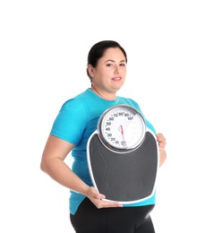 Overweight woman in sportswear with scales on white background