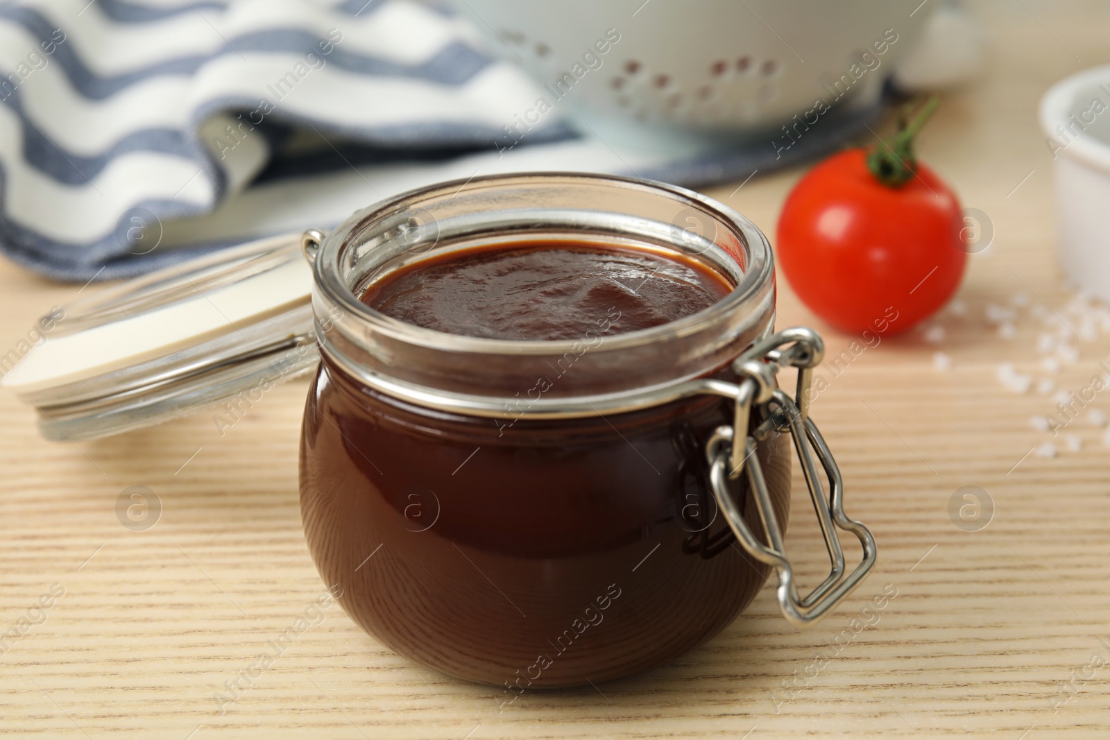 Photo of Glass jar of hot barbecue sauce on wooden table