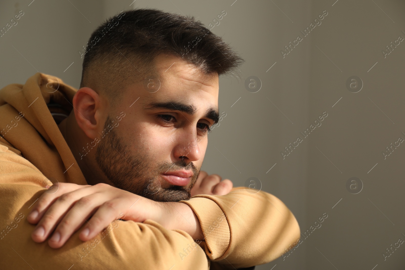 Photo of Sad young man at home. Space for text