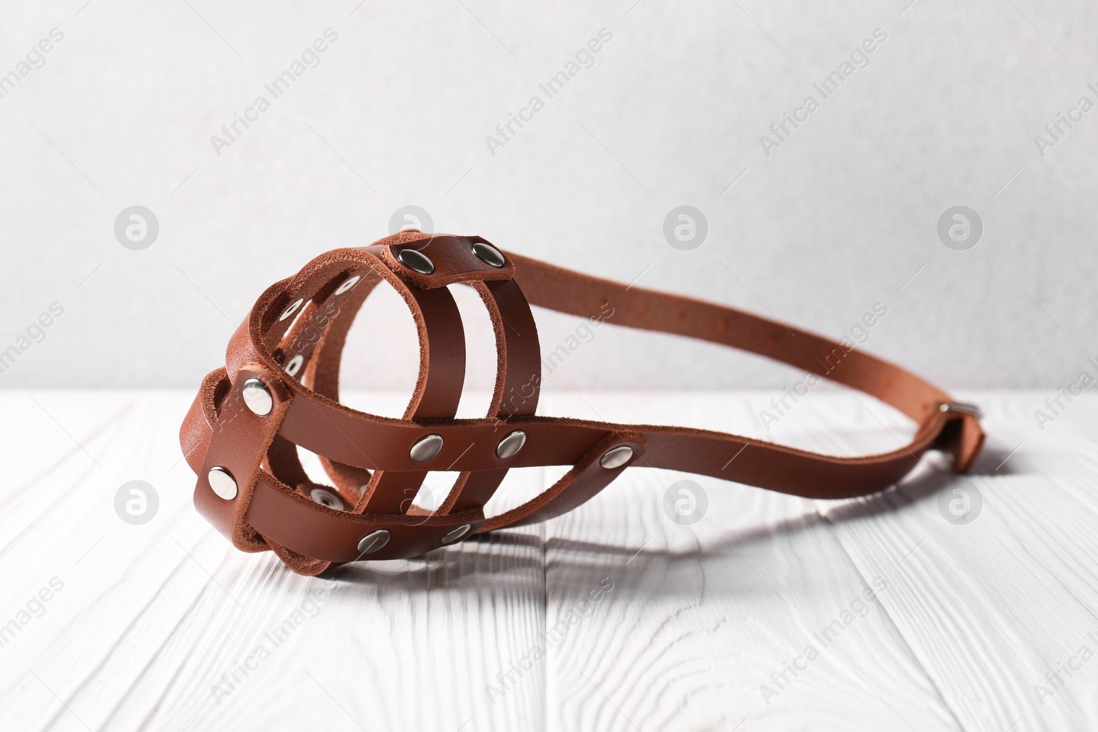 Photo of Brown leather dog muzzle on white wooden table