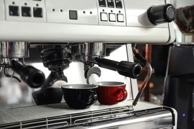 Photo of Modern coffee machine with cups in cafe, closeup