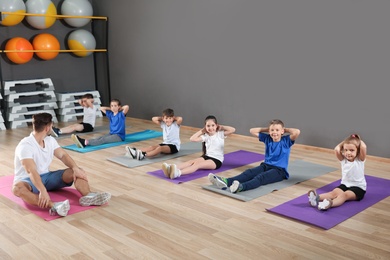 Cute little children and trainer doing physical exercise in school gym. Healthy lifestyle