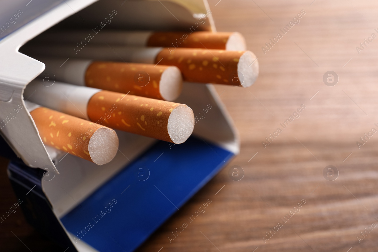 Photo of Pack of cigarettes on wooden table, closeup