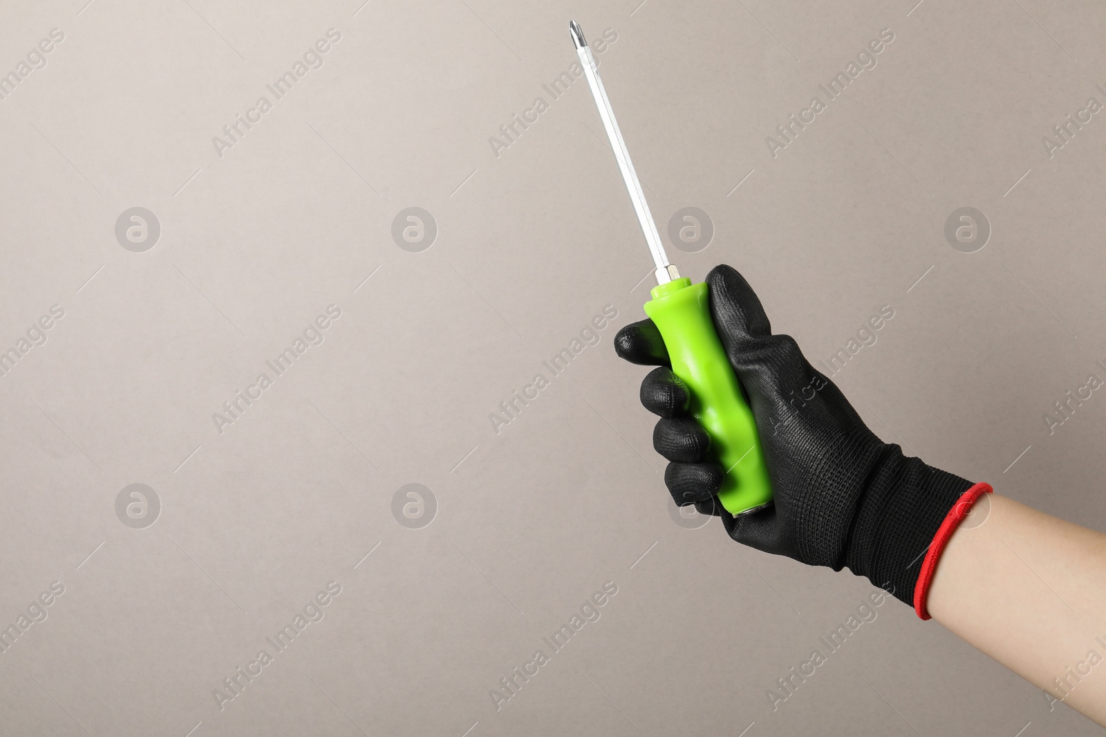 Photo of Woman holding screwdriver on grey background, closeup. Space for text