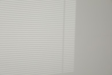 Photo of Light and shadow from window shutters on white wall, space for text