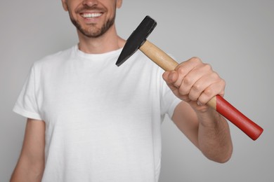 Photo of Happy worker holding hammer on white background, closeup