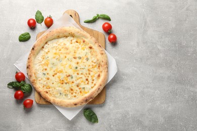 Photo of Delicious cheese pizza, basil and tomatoes on light grey table, flat lay. Space for text