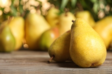 Photo of Fresh ripe pears on wooden table against blurred background