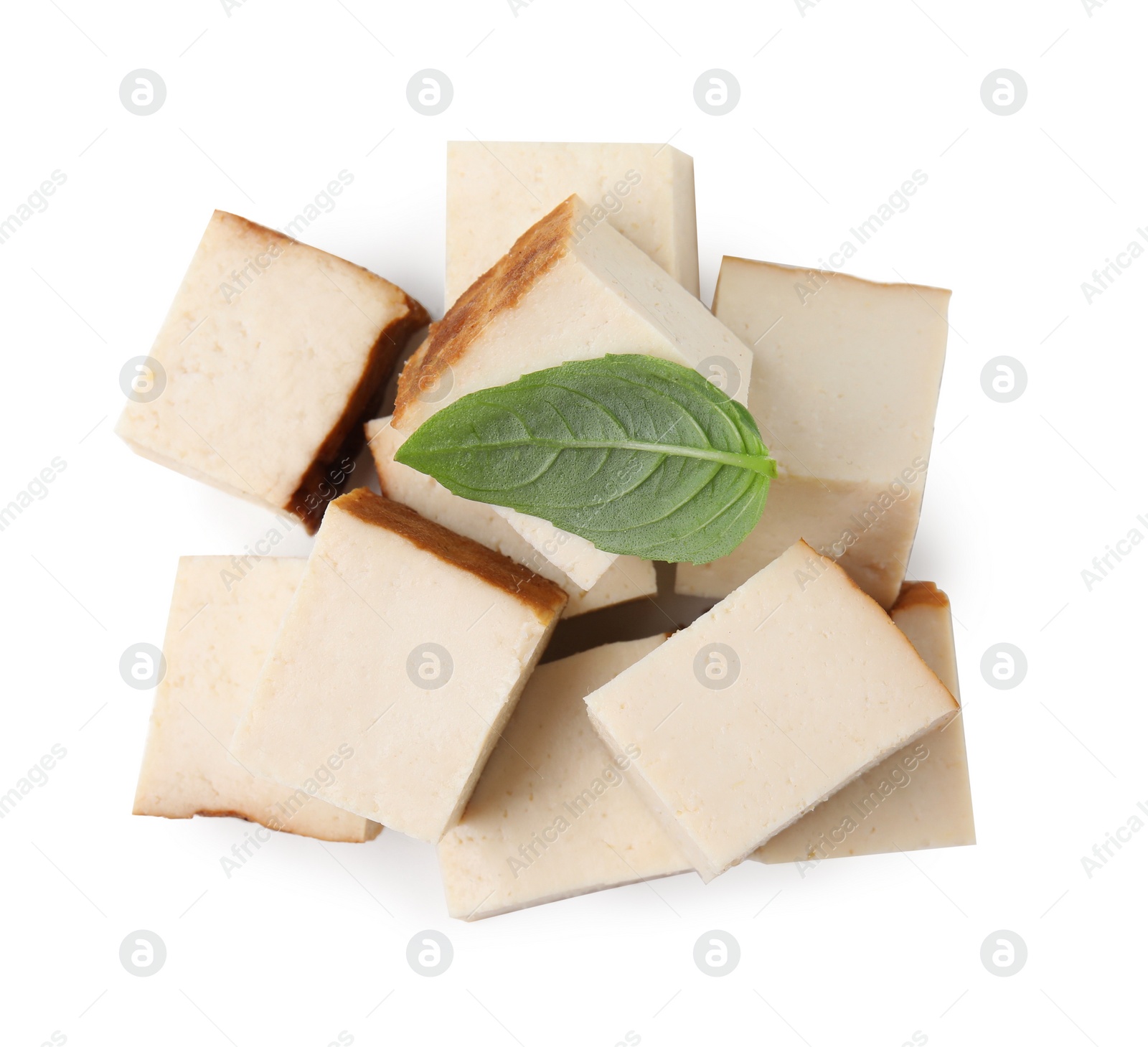 Photo of Pile of smoked tofu cubes and basil on white background, top view