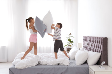 Happy children having pillow fight in bedroom