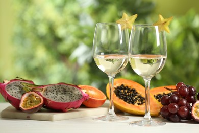 Photo of Delicious exotic fruits and wine on white table