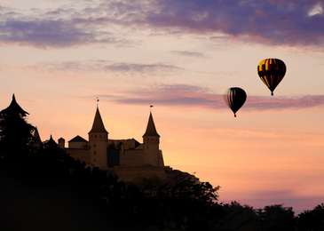 Fairy tale world. Hot air balloons flying near rock with hideaway castle