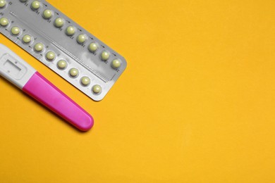 Birth control pills and pregnancy test on yellow background, top view. Space for text