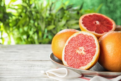 Photo of Plate of grapefruits on table against blurred background. Space for text