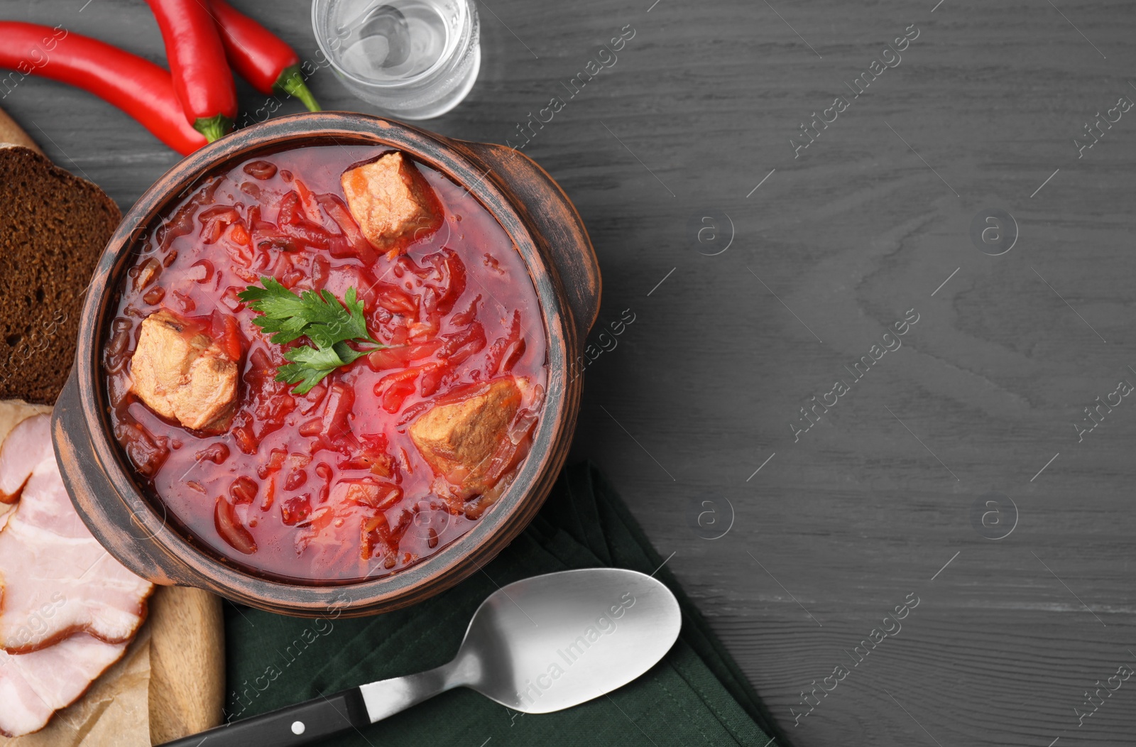 Photo of Tasty borscht in bowl served on grey wooden table, flat lay. Space for text