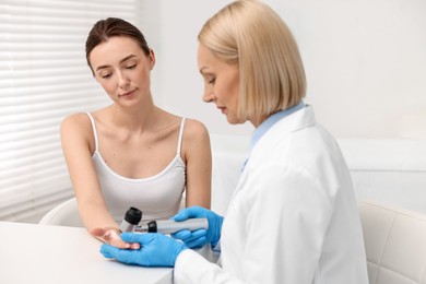 Photo of Dermatologist with dermatoscope examining patient in clinic